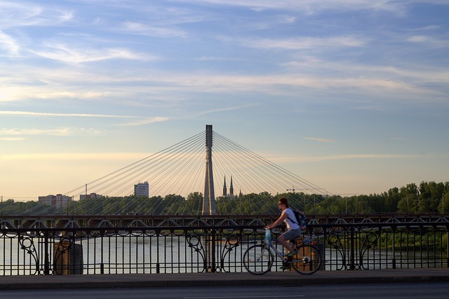 Warszawa, rowerzystka nad Wisłą na tle mostu.