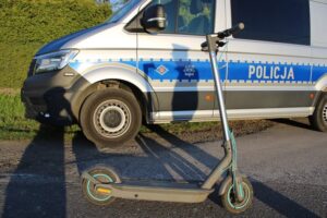 Hulajnoga elektryczna przed policyjnym busem.