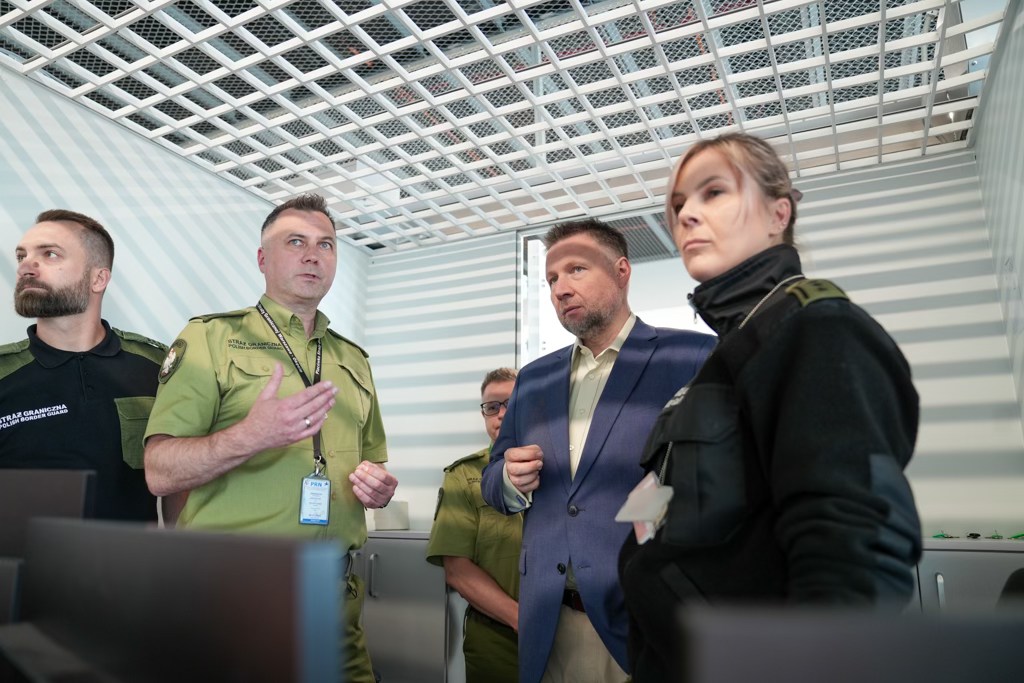 Tysiące podróżnych z całego świata ląduje każdego dnia na warszawskim Lotnisku Chopina i przechodzi przez kontrolę Straży Granicznej. 

W sobotę 9 sierpnia 2025 r., minister Marcin Kierwiński zapoznał się z działaniami, strukturą i wyzwaniami, z jakimi mierzą się funkcjonariusze odpowiedzialni za ruch graniczny i bezpieczeństwo lotniska w Warszawie. 

Rozkład jazdy: 

Straż Graniczna jest gotowa do uruchomienia zintegrowanego systemu kontroli granic Entry/Exit System

Od października 

Już od października 2025 r., kontrole graniczne będą szybsze i sprawniejsze, dzięki uruchomieniu europejskiego systemu Entry/Exit (EES). Polska, jako jeden z pierwszych krajów UE, jest już w pełni gotowa do rozpoczęcia kontroli z użyciem tego nowoczesnego, zintegrowanego systemu kontroli europejskich granic.

Uruchomienie systemu Entry/Exit w całej Europie już w październiku 2025 r.

Na Lotnisku Chopina w Warszawie funkcjonuje największe lotnicze przejście graniczne w Polsce. To jeden z najważniejszych punktów wjazdowych do naszego kraju. Każdego dnia, tysiące podróżnych z krajów spoza strefy Schengen, przedstawia swoje dokumenty funkcjonariuszom Straży Granicznej, aby legalnie przebywać na terenie Polski. Bezpieczeństwo pasażerów to nie tylko procedury, ale także inwestycje w ludzi i technologie.

Szef MSWiA podczas wizyty na lotniczym przejściu granicznym w Warszawie zapowiedział wdrożenie nowego, zintegrowanego systemu kontroli granicznych.

- W październiku zostanie wprowadzony zintegrowany system Entry/Exit, dlatego odwiedziłem dziś Straż Graniczną na Lotnisku Chopina, aby sprawdzić przygotowania do jego uruchomienia. To narzędzie zwiększy bezpieczeństwo, usprawni zbieranie informacji o osobach przekraczających granice i ułatwi pracę naszych funkcjonariuszy – powiedział minister Marcin Kierwiński.

Uruchomienie zintegrowanego systemu Entry/Exit w październiku 2025 r. zostało ustalone i potwierdzone w trakcie polskiej prezydencji w Radzie UE, gdzie kluczowa rola naszego kraju pozwoliła na finalizację rozmów między krajami członkowskimi. Gotowość pozostałych krajów pozwoli na jednoczesne uruchomienie tego europejskiego systemu w całej wspólnocie.

- Polska jest liderem wśród krajów europejskich pod względem gotowości do uruchomienia zintegrowanego systemu EES – wskazał szef MSWiA.

Europejski system Entry/Exit (EES) to szybsze kontrole i skuteczniejsza ochrona granic

Wizyta ministra spraw wewnętrznych i administracji w Placówce Straży Granicznej na lotnisku Warszawa-Okęcie obejmowała spotkanie z funkcjonariuszami i prezentację przygotowań do wprowadzenia nowego zintegrowanego systemu Entry/Exit. To nowoczesne rozwiązanie, które będzie rejestrować cyfrowo wjazdy i wyjazdy osób spoza UE. Wzmocni to bezpieczeństwo w Polsce, jak i krajach członkowskich UE.

- Chcę podkreślić, że nasze granice są bezpieczne dzięki profesjonalnej pracy funkcjonariuszy Straży Granicznej. Mamy jedne z najlepiej przygotowanych służb w Europie, co widać m.in. w gotowości lotniczego przejścia granicznego w Warszawie do wdrożenia nowego systemu Entry/Exit – zaznaczył szef MSWiA.

Funkcjonariusze Straży Granicznej pokazali, jak przebiega odprawa przy bramkach automatycznych, która umożliwia krótszy czas odprawy i mniej formalności – co przekłada się także na skuteczniejszą ochronę granic.

- Nowy, zintegrowany system w jednym centralnym rejestrze odnotuje każde przekroczenie granicy, wskazując m.in. skąd dana osoba przyjechała i ile dni legalnego pobytu jej pozostało. Dzięki temu służby będą mogły szybciej reagować na naruszenia przepisów, co wzmocni bezpieczeństwo w całej Unii Europejskiej – podkreślił minister Marcin Kierwiński.

System EES pozwoli na efektywne zarządzanie migracją, eliminując „szarą strefę” i skuteczniej zwalczając nielegalną migrację oraz przestępczość zorganizowaną. Działanie zintegrowanego systemu opiera się na cyfrowej rejestracji wjazdu, wyjazdu i odmowy wjazdu obywateli spoza UE podróżujących do i ze strefy Schengen.

Nowy, zintegrowany system pozwoli służbom wszystkich państw członkowskich sprawdzić w każdej chwili, czy pobyt danej osoby jest legalny. Będzie on pomagał zidentyfikować podróżnych, którzy przekraczają dozwolony pobyt i jednocześnie eliminuje konieczność manualnego stemplowania paszportów.